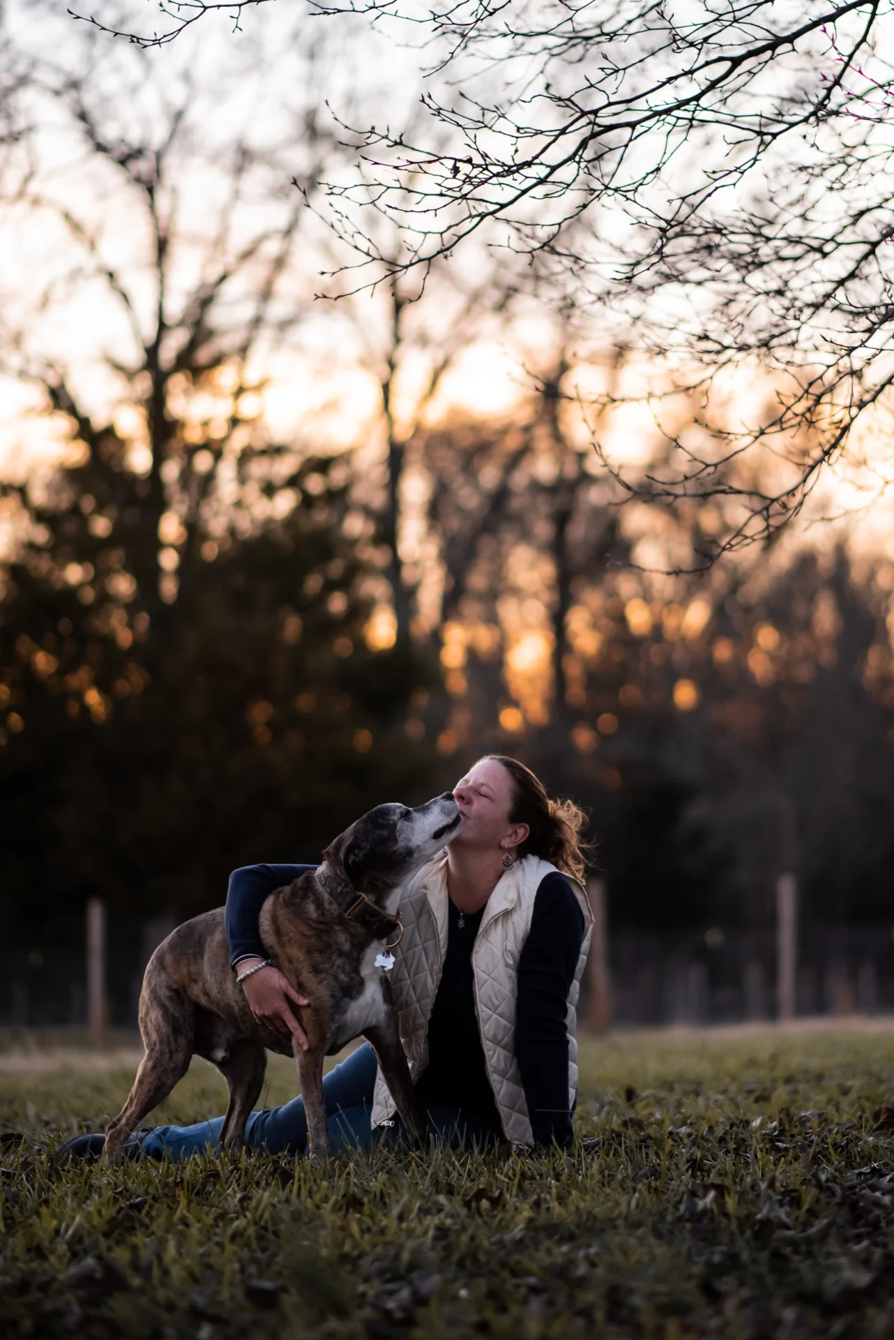 A woman and her dog are playing in the grass.